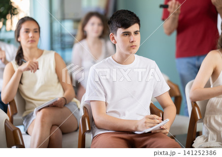 Group of students listening to lecture with teacher in background Group of students listening to lecture with teacher in background 141252386