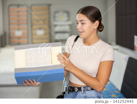 Girl chooses mattress filling in furniture store Girl chooses mattress filling in furniture store 141252443