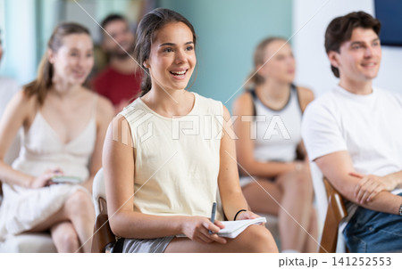 At meeting room during lecture, girl with classmates listen and laughing At meeting room during lecture, girl with classmates listen and laughing 141252553