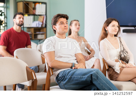 European guy is sitting among a group of people in an audience and listening to a lecture European guy is sitting among a group of people in an audience and listening to a lecture 141252597
