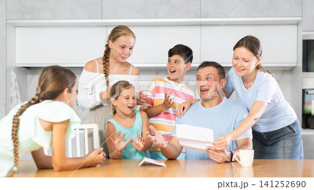 Joyful father of family with children and wife read letter in kitchen. Joyful father of family with children and wife read letter in kitchen. 141252690