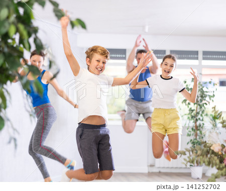 Happy preteen boy and girl jumping joyfully with their parents in training room 141252702