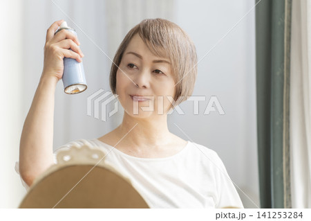スプレーでヘアスタイルを整えるシニア女性 スプレーでヘアスタイルを整えるシニア女性 141253284