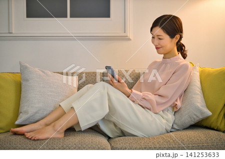 夜部屋でリラックスしてスマホを見る40代の女性 夜部屋でリラックスしてスマホを見る40代の女性 141253633