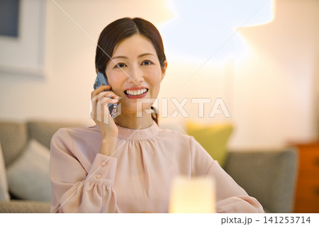 夜部屋でリラックスしてスマホを見る40代の女性 夜部屋でリラックスしてスマホを見る40代の女性 141253714