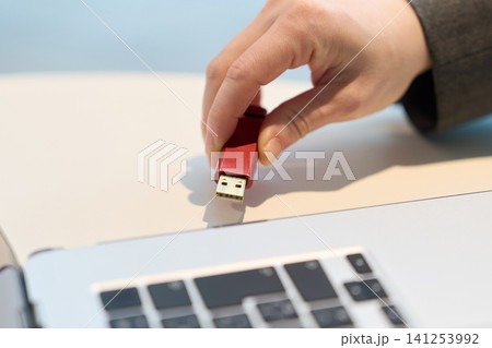 パソコンにUSBメモリを挿す手元 141253992