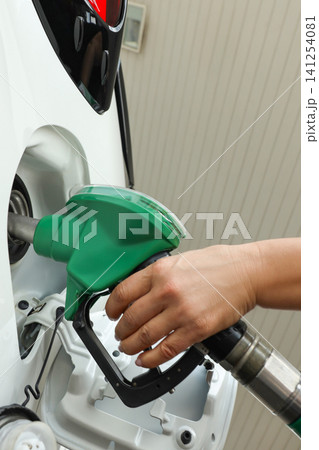 A person is filling a white vehicle with fuel at a station A person is filling a white vehicle with fuel at a station 141254081