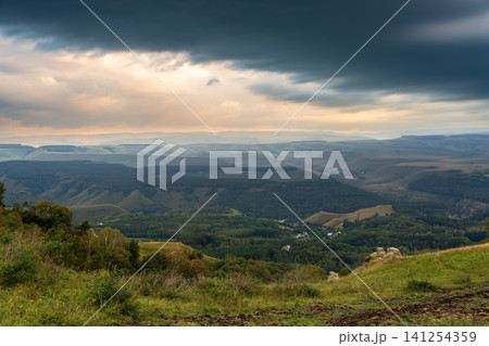 Layers of green mountains and hills in the haze during sunset. Panoramic View of Green hills and Meadow. 141254359