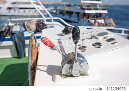 Boat control lever features throttle and gear shift on a yacht deck, with additional boats and the sea visible in the background Boat control lever features throttle and gear shift on a yacht deck, with additional boats and the sea visible in the background 141254676