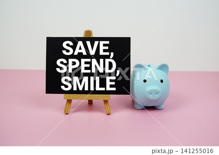 Save, Spend, Smile text written on paper card with easel and piggy bank Save, Spend, Smile text written on paper card with easel and piggy bank 141255016