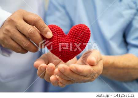 Doctor holding a red heart in hospital, healthy strong medical concept. Doctor holding a red heart in hospital, healthy strong medical concept. 141255112