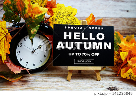 Hello Autumn Sale 70% off Special Offer text with alarm clock and maple leaf decoration on wooden background 141256849