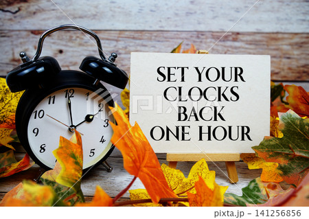 Set Your Clocks Back One Hour text with alarm clock and maple leaf decoration on wooden background Set Your Clocks Back One Hour text with alarm clock and maple leaf decoration on wooden background 141256856