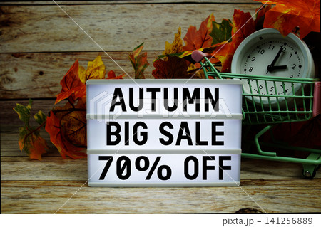 Autumn Big Sale 70% off text with trolley shopping cart and alarm clock decoration with maple leaf on wooden background Autumn Big Sale 70% off text with trolley shopping cart and alarm clock decoration with maple leaf on wooden background 141256889