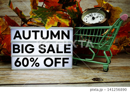 Autumn Big Sale 60% off text with trolley shopping cart and alarm clock decoration with maple leaf on wooden background Autumn Big Sale 60% off text with trolley shopping cart and alarm clock decoration with maple leaf on wooden background 141256890