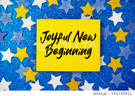 Joyful New Beginning text written on paper card with star glitter on blue background Joyful New Beginning text written on paper card with star glitter on blue background 141256912