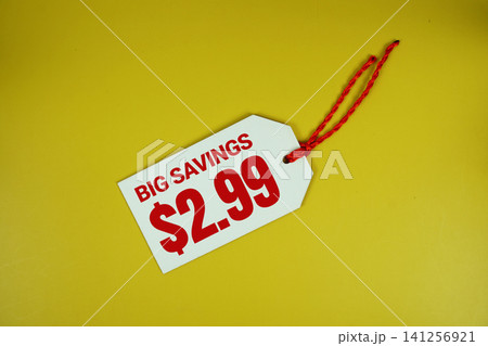 Big Savings $2.99 text message on price tag top view on yellow background, business and promotion concep Big Savings $2.99 text message on price tag top view on yellow background, business and promotion concep 141256921