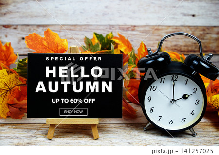 Hello Autumn Sale 60% off Special Offer text with alarm clock and maple leaf decoration on wooden background Hello Autumn Sale 60% off Special Offer text with alarm clock and maple leaf decoration on wooden background 141257025