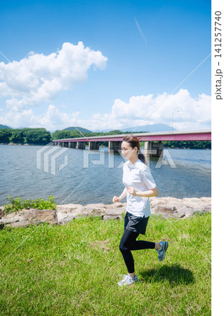 湖畔でランニングする女性の全身 湖畔でランニングする女性の全身 141257740