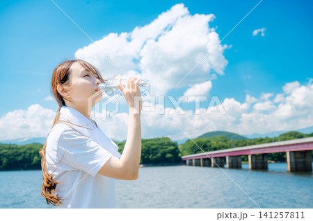 湖畔で水分補給する女性 湖畔で水分補給する女性 141257811