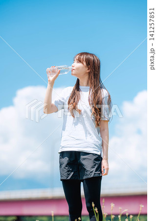 青空を仰ぎ水を飲む女性の全身ポートレート 青空を仰ぎ水を飲む女性の全身ポートレート 141257851