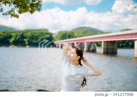 橋を背景に髪に手を添える女性 橋を背景に髪に手を添える女性 141257986