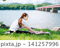 橋を背景に前屈ストレッチをするポニーテールの女性 141257996