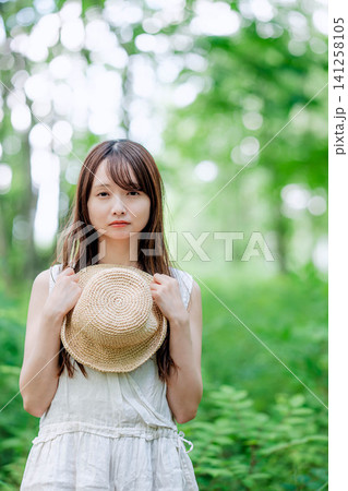 麦わら帽子を手に前を見すえる女性 麦わら帽子を手に前を見すえる女性 141258105