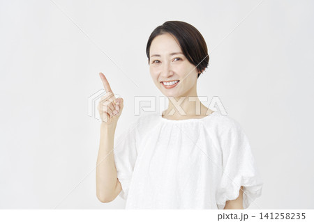 左側を指差すミドルエイジ女性　白背景 141258235
