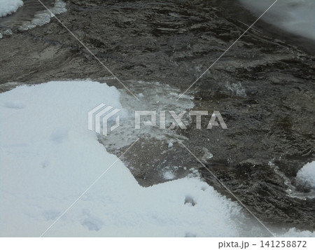 Closeup on flowing cold river during snowy winter Closeup on flowing cold river during snowy winter 141258872