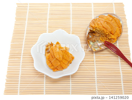 三陸名産の焼きウニを半分取り分けて皿に盛るイメージ 三陸名産の焼きウニを半分取り分けて皿に盛るイメージ 141259020