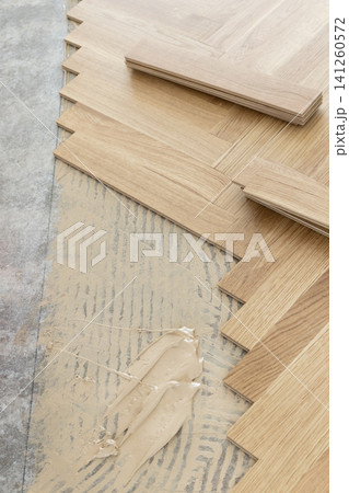 Oak herringbone parquet flooring installation with adhesive on concrete subfloor top view Oak herringbone parquet flooring installation with adhesive on concrete subfloor top view 141260572