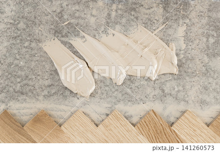 Oak herringbone parquet flooring installation with adhesive on concrete subfloor top view Oak herringbone parquet flooring installation with adhesive on concrete subfloor top view 141260573