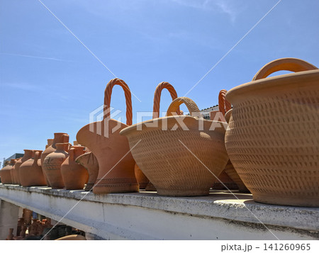 Terracotta clay baskets with woven handles are arranged in rows outdoors. The bright blue sky adds to the scene of artisan craftsmanship and garden decor. Terracotta clay baskets with woven handles are arranged in rows outdoors. The bright blue sky adds to the scene of artisan craftsmanship and garden decor. 141260965