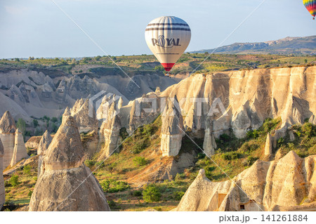 Hot air balloon flies over rock formations in Cappadocia during daylight hours. 05.11.2018. Cappadocia. Turkey Hot air balloon flies over rock formations in Cappadocia during daylight hours. 05.11.2018. Cappadocia. Turkey 141261884