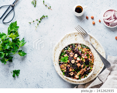 Vegetarian diet salad with beet, buckwheat grains, mushrooms, red onion and fresh herbs in bowl. Warm buckwheat and beetroot salad on gray concrete background. Top view. Copy space Vegetarian diet salad with beet, buckwheat grains, mushrooms, red onion and fresh herbs in bowl. Warm buckwheat and beetroot salad on gray concrete background. Top view. Copy space 141262935