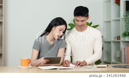 Asian couple managing home budget and bills with tablet at table Asian couple managing home budget and bills with tablet at table 141263480