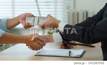 Bribery and corruption concept with hands shaking and passing money over contract Bribery and corruption concept with hands shaking and passing money over contract 141263502