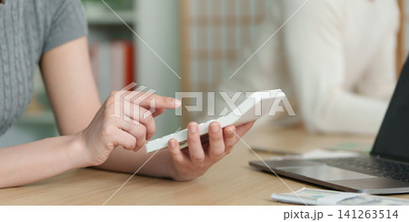 Cropped hands of woman using calculator for financial planning and budgeting 141263514