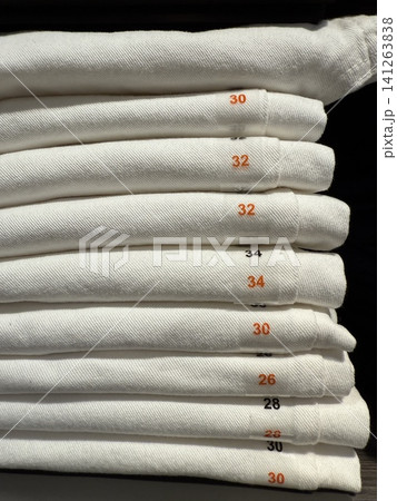 White denim jeans arranged by size in vertical display for a retail fashion concept background White denim jeans arranged by size in vertical display for a retail fashion concept background 141263838