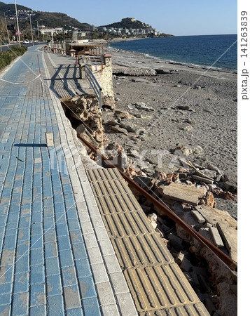 Damaged seaside promenade with crumbled pavement and exposed rocks on a sunny day Damaged seaside promenade with crumbled pavement and exposed rocks on a sunny day 141263839