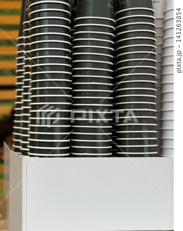 Stacks of disposable coffee cups in holder against colorful striped wall, available as background Stacks of disposable coffee cups in holder against colorful striped wall, available as background 141263854