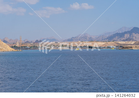 Scenic coastal view of a resort town featuring mountains, clear blue water, and a bright sky in a desert landscape Scenic coastal view of a resort town featuring mountains, clear blue water, and a bright sky in a desert landscape 141264032