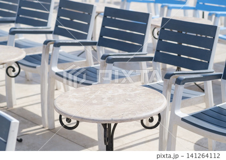 Outdoor seating area showcases several blue and white lounge chairs positioned around a small round table on a bright sunny day Outdoor seating area showcases several blue and white lounge chairs positioned around a small round table on a bright sunny day 141264112