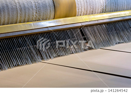 Close up of corrugated cardboard sheets moving through industrial brush roller machine 141264542