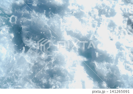 Close-up view of ocean waves crashing, producing white foam and splashes under bright sunlight, with a clear blue background visible Close-up view of ocean waves crashing, producing white foam and splashes under bright sunlight, with a clear blue background visible 141265091