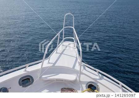 Bow of a white motorboat features a railing, with expansive blue ocean waters visible under bright sunlight on a clear day Bow of a white motorboat features a railing, with expansive blue ocean waters visible under bright sunlight on a clear day 141265097