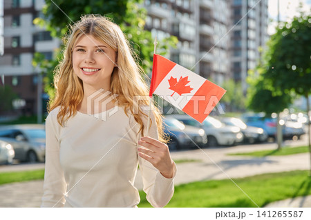 Beautiful young woman holding small flag of Canada Beautiful young woman holding small flag of Canada 141265587