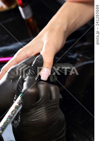 A woman's hand during a manicure. A woman getting a manicure. A manicurist is doing a client's nails at a nail salon. Manicure services. Nail art. Beauty salon. 141265689