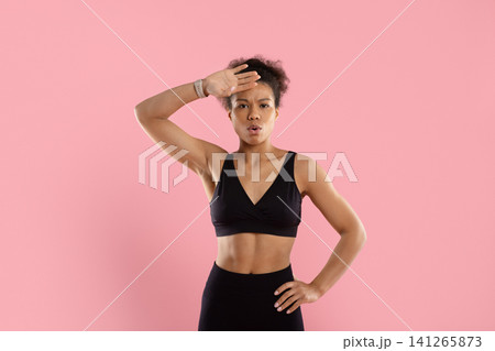 Tired young Black athletic woman wiping sweat from her forehead after exercise 141265873
